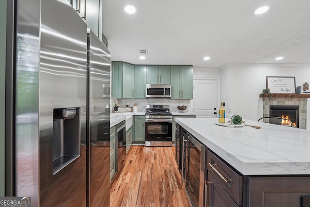 kitchen with wine cooler, visible vents, light wood-style flooring, green cabinetry, and appliances with stainless steel finishes