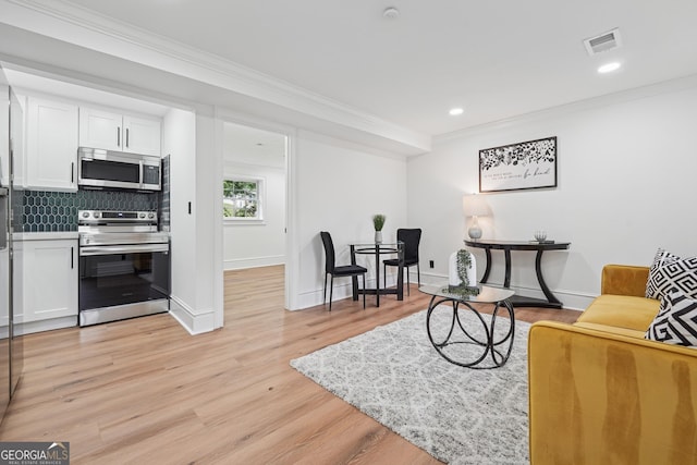 living area featuring baseboards, visible vents, light wood-style flooring, and crown molding