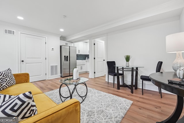 living room with visible vents, recessed lighting, ornamental molding, and light wood-style floors