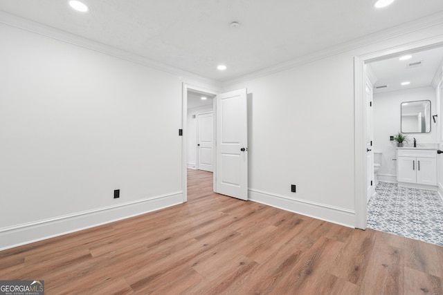 unfurnished bedroom featuring crown molding, light wood finished floors, and a sink