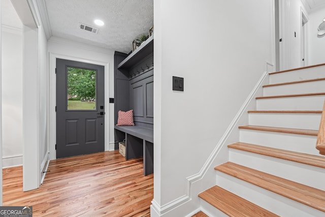 mudroom featuring recessed lighting, ornamental molding, light wood finished floors, visible vents, and a textured ceiling
