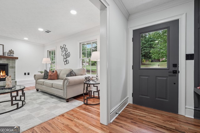 entrance foyer featuring a tile fireplace, crown molding, light wood-style flooring, and recessed lighting