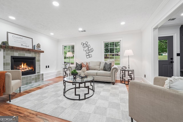 living room featuring crown molding, recessed lighting, visible vents, and a fireplace
