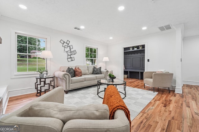 living room with wood finished floors, visible vents, recessed lighting, and ornamental molding