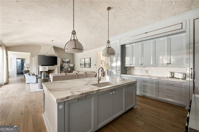 kitchen featuring a sink, gray cabinetry, vaulted ceiling, and hardwood / wood-style flooring
