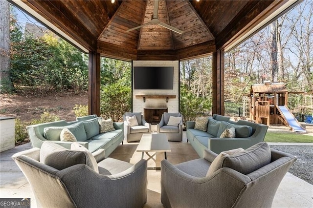view of patio with ceiling fan, a playground, a gazebo, and an outdoor living space with a fireplace