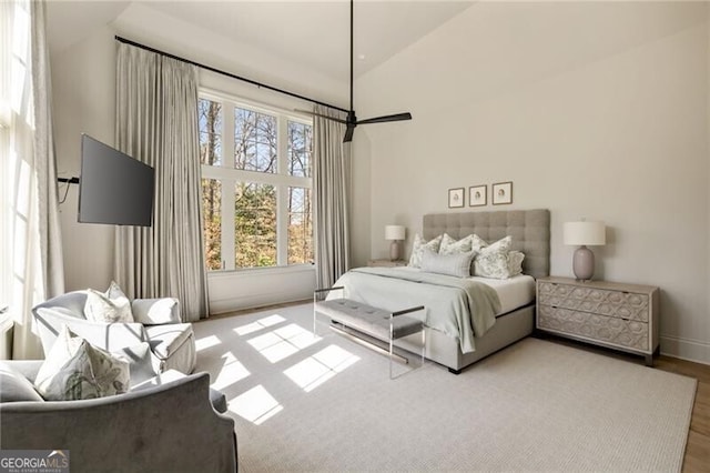 bedroom with wood finished floors, baseboards, and a high ceiling