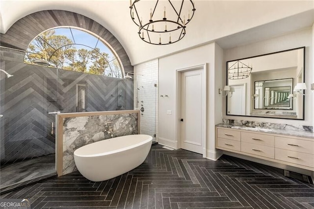 bathroom featuring a freestanding bath, an inviting chandelier, a tile shower, and vanity