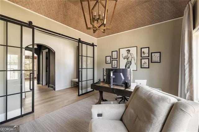 office area with crown molding, a barn door, arched walkways, a chandelier, and wood finished floors