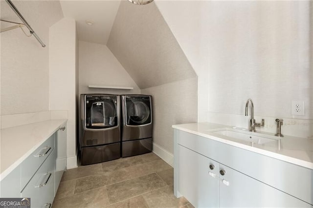 clothes washing area featuring baseboards, a sink, cabinet space, and washer and dryer