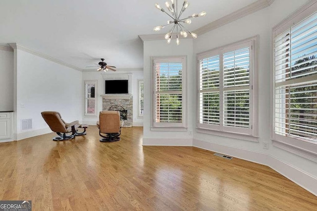 2932 Springbluff Ln, Buford, GA 30519 - sitting room featuring wood finished floors, ceiling fan with notable chandelier, a stone fireplace, visible vents, and crown molding
