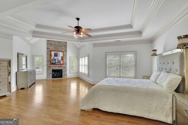 2932 Springbluff Ln, Buford, GA 30519 - bedroom with a tray ceiling, crown molding, a stone fireplace, light wood-style flooring, and baseboards