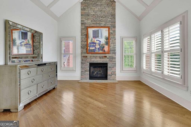2932 Springbluff Ln, Buford, GA 30519 - living room featuring a stone fireplace, high vaulted ceiling, baseboards, and light wood-type flooring