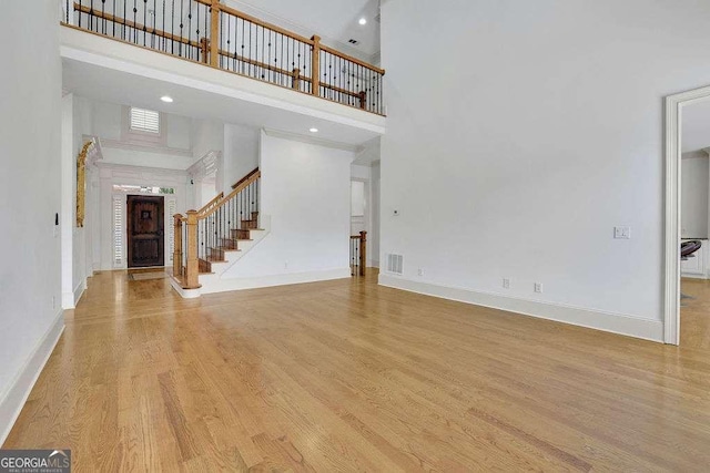 2932 Springbluff Ln, Buford, GA 30519 - unfurnished living room featuring baseboards, stairway, wood finished floors, and a towering ceiling