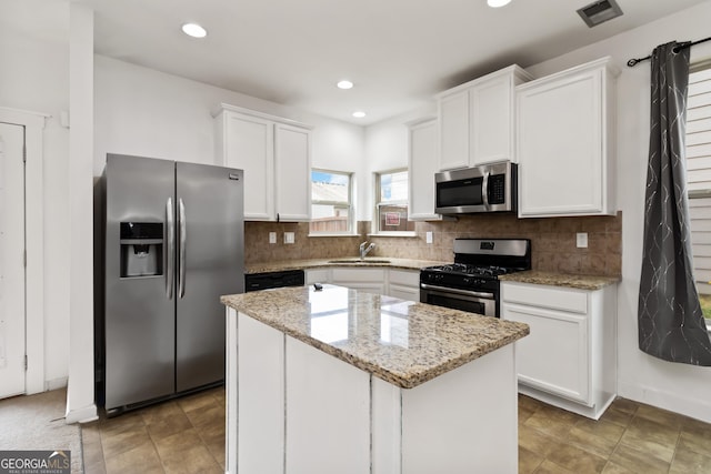 kitchen featuring stainless steel appliances, white cabinets, a center island, a sink, and recessed lighting