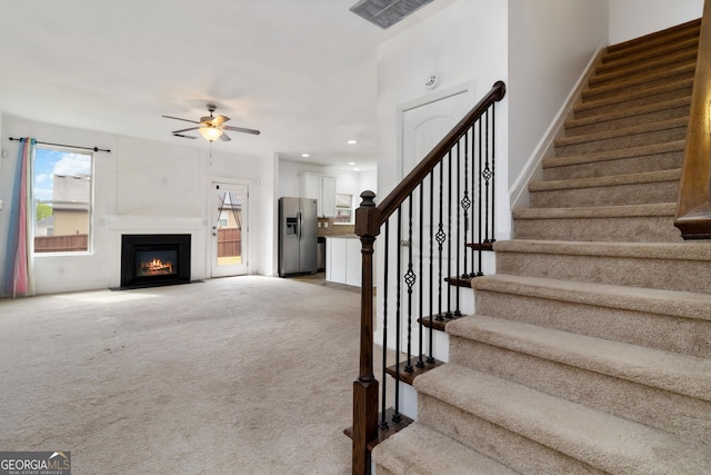 stairs with ceiling fan, carpet floors, baseboards, recessed lighting, and a fireplace with flush hearth