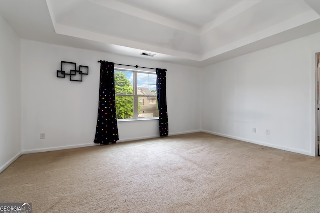 spare room featuring a raised ceiling, carpet flooring, and baseboards