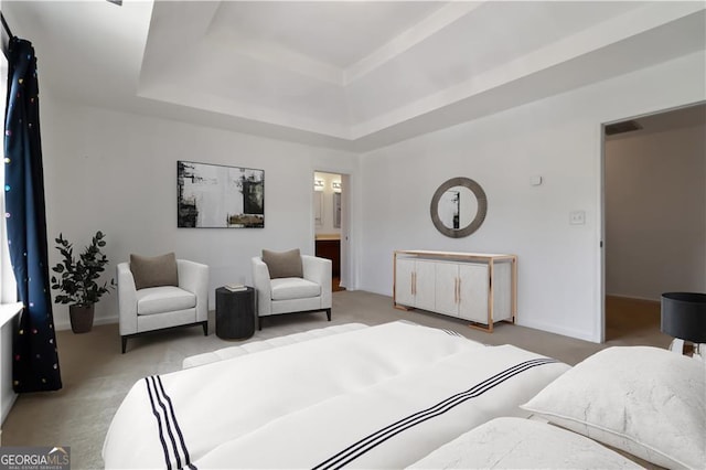 carpeted bedroom with a tray ceiling, baseboards, and ensuite bath