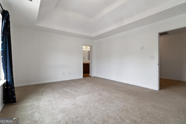 carpeted empty room with a raised ceiling and baseboards