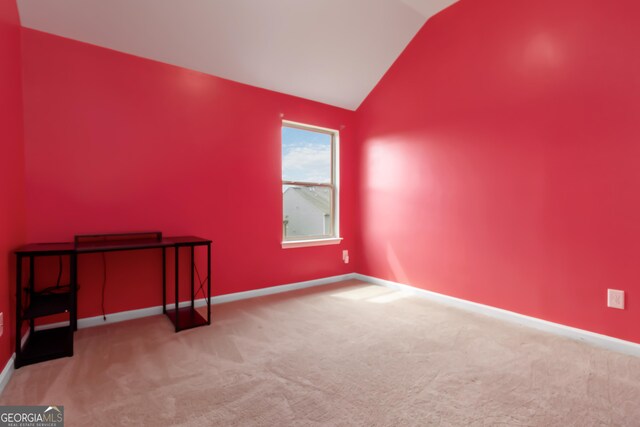 carpeted empty room with lofted ceiling and baseboards