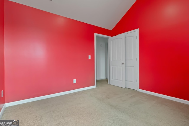 unfurnished bedroom with carpet flooring, vaulted ceiling, and baseboards