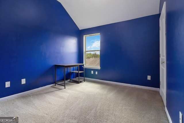 empty room featuring vaulted ceiling, carpet floors, and baseboards