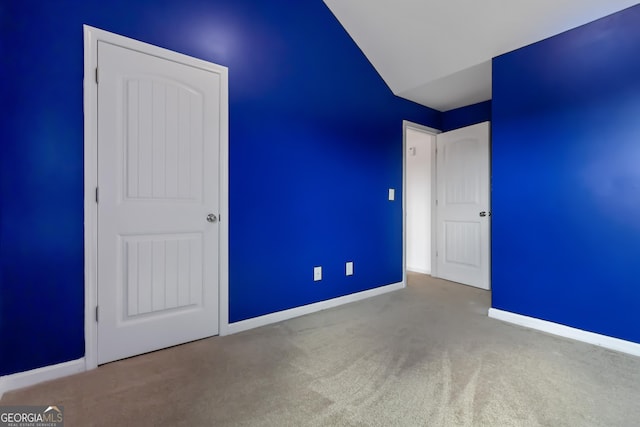 unfurnished bedroom featuring carpet, baseboards, and lofted ceiling