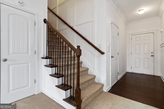 foyer entrance featuring ornamental molding, stairway, carpet, and baseboards