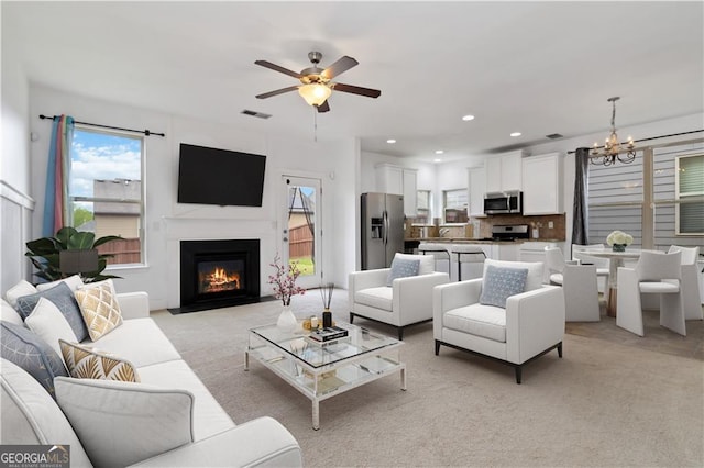 living room featuring a chandelier, ceiling fan, light carpet, a fireplace with flush hearth, and recessed lighting