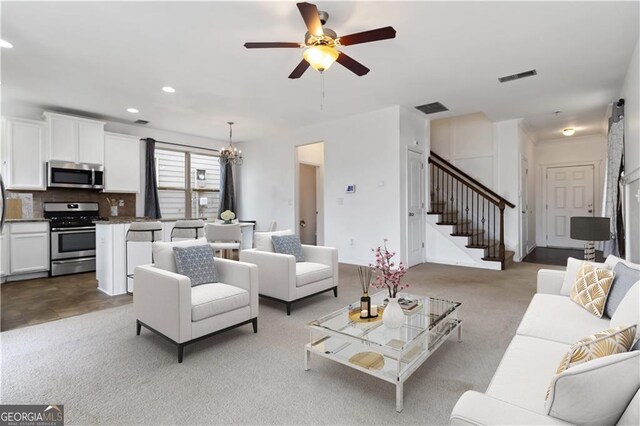 carpeted living room featuring stairway, recessed lighting, ceiling fan, and a chandelier