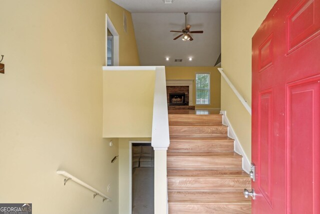 140 Spring Cir, Senoia, GA 30276 - stairs featuring wood finished floors, a brick fireplace, visible vents, a ceiling fan, and high vaulted ceiling