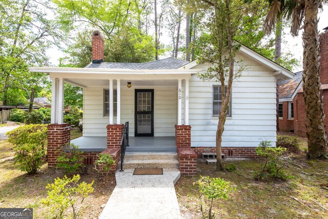bungalow-style house featuring covered porch and a chimney