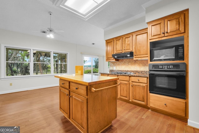 45 Herons Nest, Savannah, GA 31410 - kitchen featuring tasteful backsplash, a kitchen island, under cabinet range hood, black appliances, and light wood-type flooring