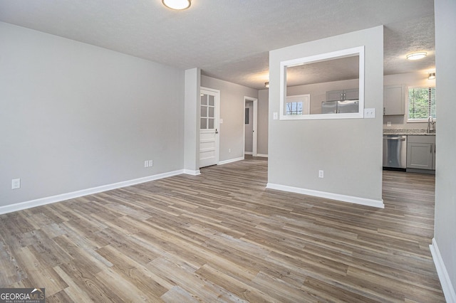 898 Doeskin Dr NW, Conyers, GA 30012 - unfurnished living room with wood finished floors, baseboards, a sink, and a textured ceiling