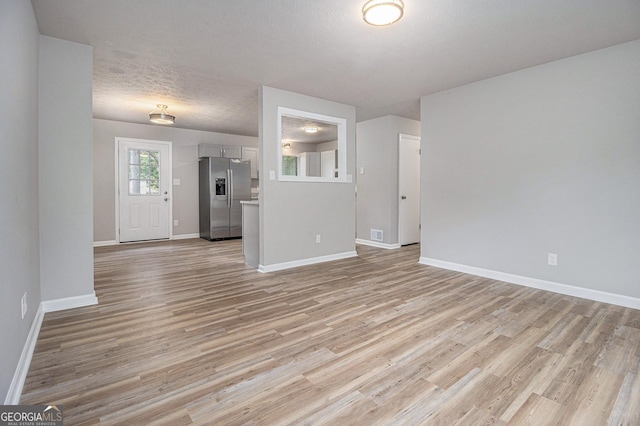 898 Doeskin Dr NW, Conyers, GA 30012 - unfurnished living room with light wood-style floors, baseboards, and a textured ceiling
