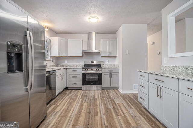 898 Doeskin Dr NW, Conyers, GA 30012 - kitchen with appliances with stainless steel finishes, wall chimney exhaust hood, light wood-type flooring, a sink, and light stone countertops