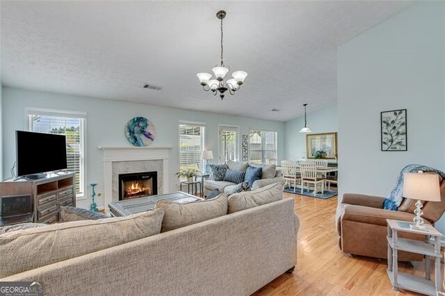 2602 Midler Ct, Buford, GA 30519 - living area featuring light wood-style floors, a chandelier, a fireplace, and a textured ceiling