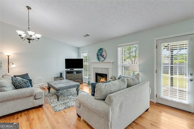 2602 Midler Ct, Buford, GA 30519 - living area with a chandelier, light wood finished floors, a fireplace, a textured ceiling, and vaulted ceiling