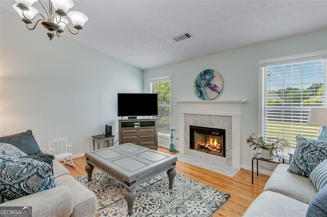 2602 Midler Ct, Buford, GA 30519 - living area featuring a chandelier, a textured ceiling, a premium fireplace, light wood-style flooring, and vaulted ceiling