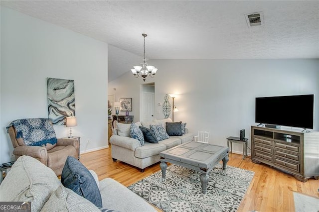 2602 Midler Ct, Buford, GA 30519 - living room with a chandelier, a textured ceiling, light wood-style floors, and vaulted ceiling
