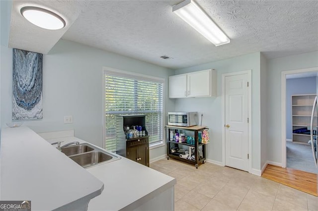 2602 Midler Ct, Buford, GA 30519 - kitchen featuring stainless steel microwave, white cabinets, a textured ceiling, light tile patterned floors, and a peninsula