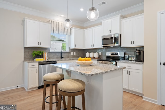 1027 Victoria Heights Dr, Dallas, GA 30132 - kitchen featuring appliances with stainless steel finishes, a center island, a breakfast bar, white cabinetry, and light wood-style floors
