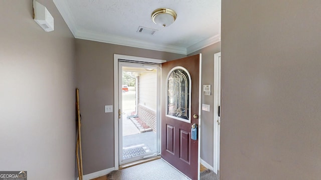 carpeted foyer entrance featuring ornamental molding, visible vents, and baseboards