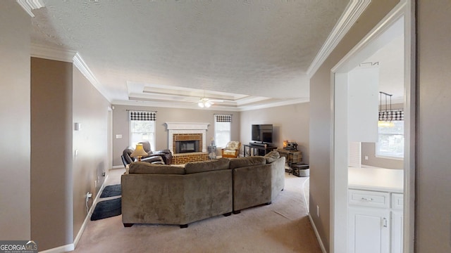 living area featuring a brick fireplace, a raised ceiling, crown molding, a ceiling fan, and light carpet