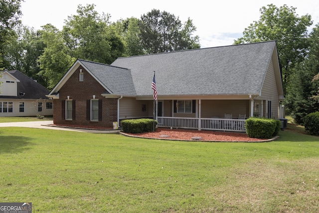 view of front facade featuring a porch, a front yard, brick siding, and roof with shingles