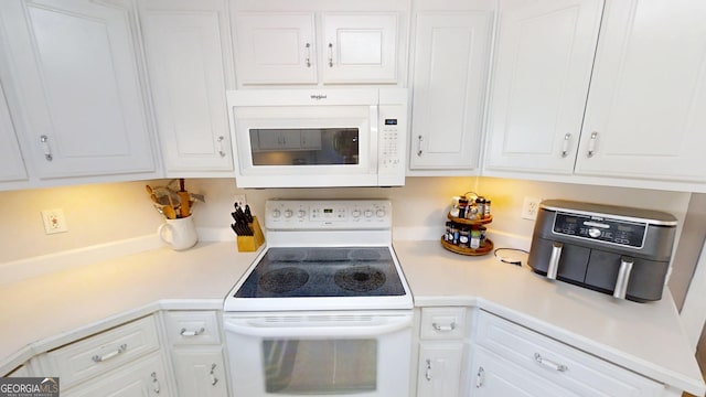 kitchen featuring white cabinets, white appliances, and light countertops