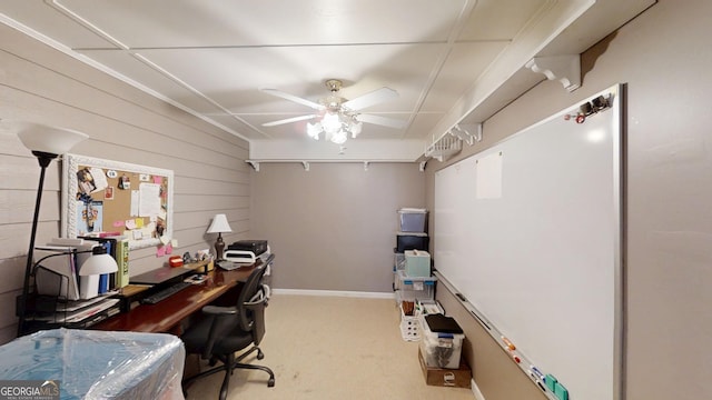 home office with wood walls, a ceiling fan, and carpet flooring