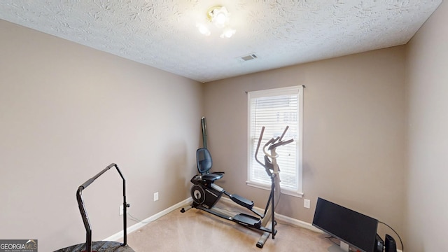 workout area with a textured ceiling, visible vents, light colored carpet, and baseboards