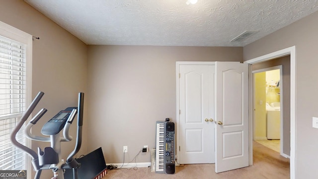 workout room featuring visible vents, washer / dryer, baseboards, and light carpet