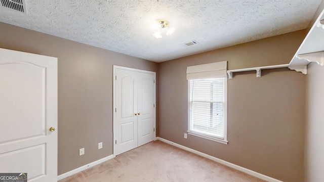 unfurnished bedroom featuring a closet, visible vents, light carpet, and baseboards